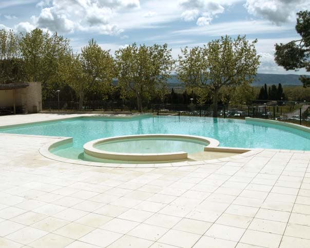 Grande piscine en forme libre avec un bassin rond, plage en dalles claires.