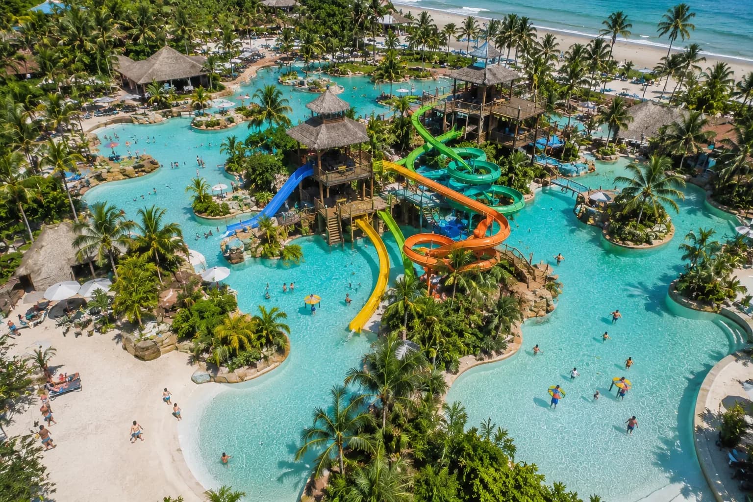 Parc aquatique tropical vu du ciel : lagons sinueux, îlots, toboggans, paillotes.