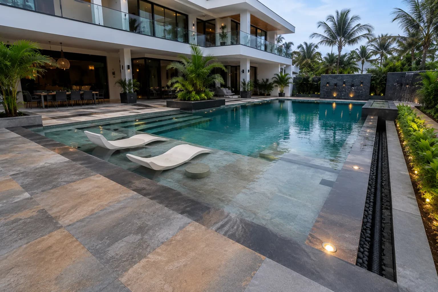 Piscine contemporaine à plage immergée, bains de soleil posés dans l'eau, villa au fond.