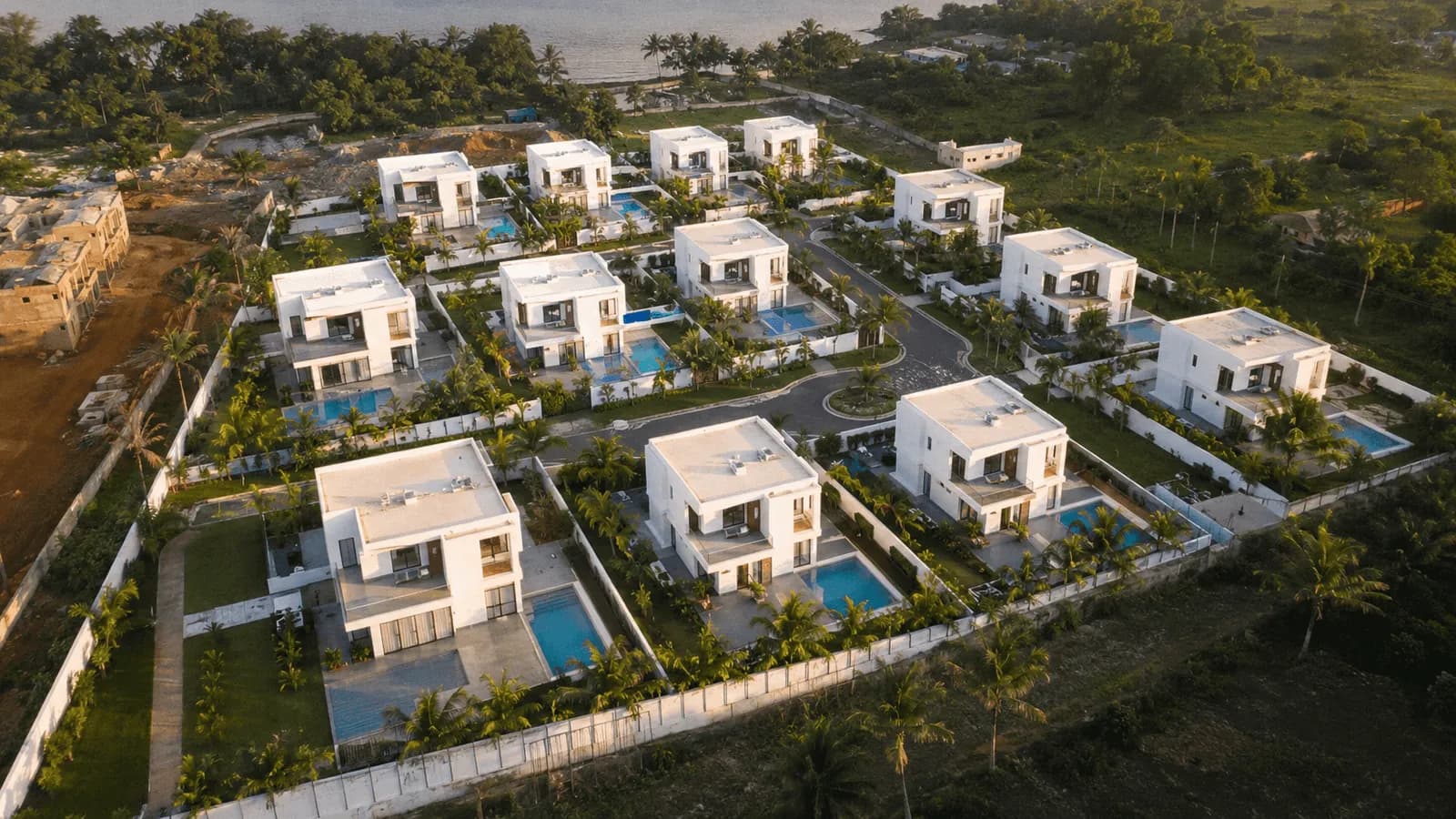 Vue aérienne d'un ensemble de villas blanches, chacune avec sa piscine.