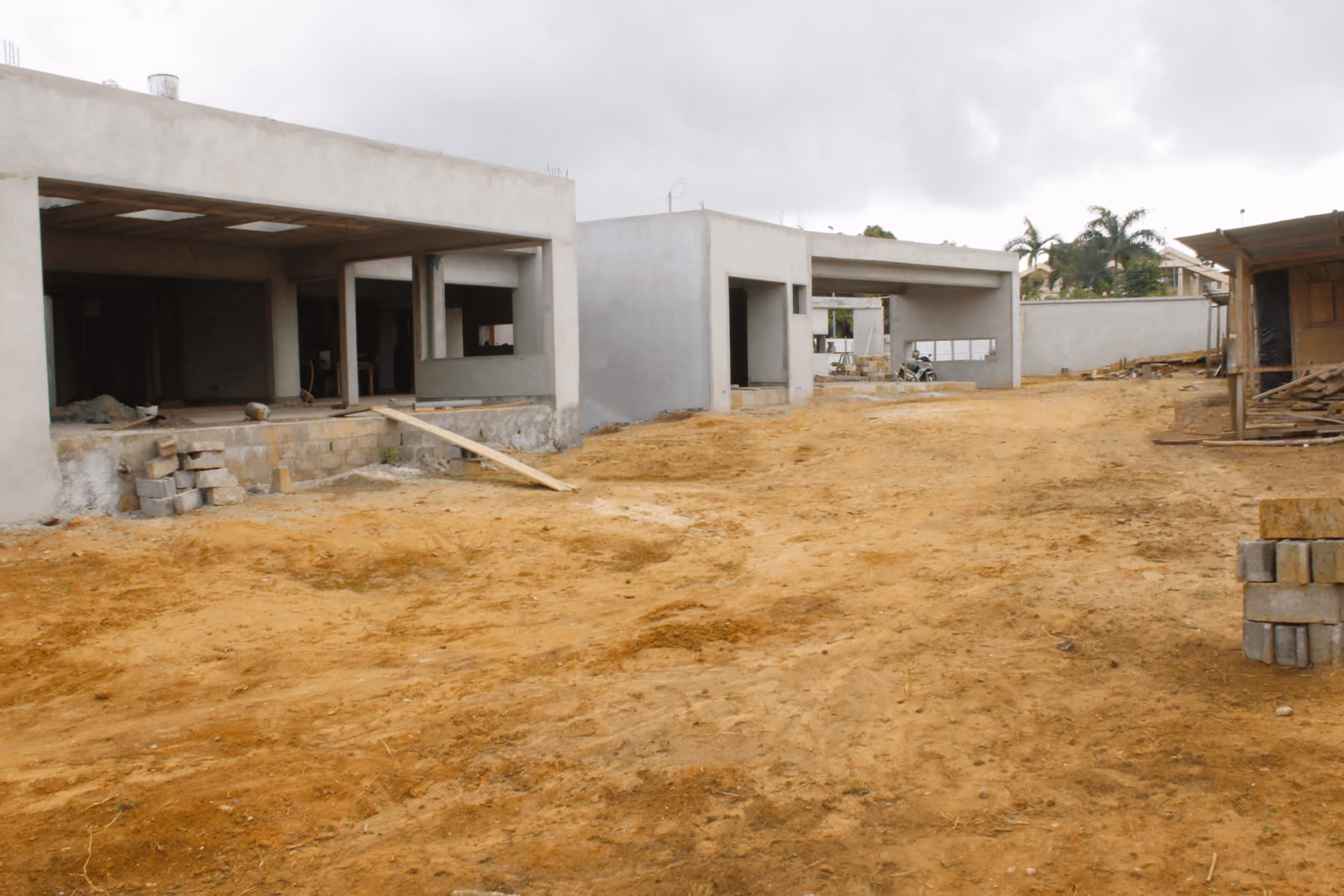 Villas de plain-pied en gros œuvre le long d'une allée en latérite.