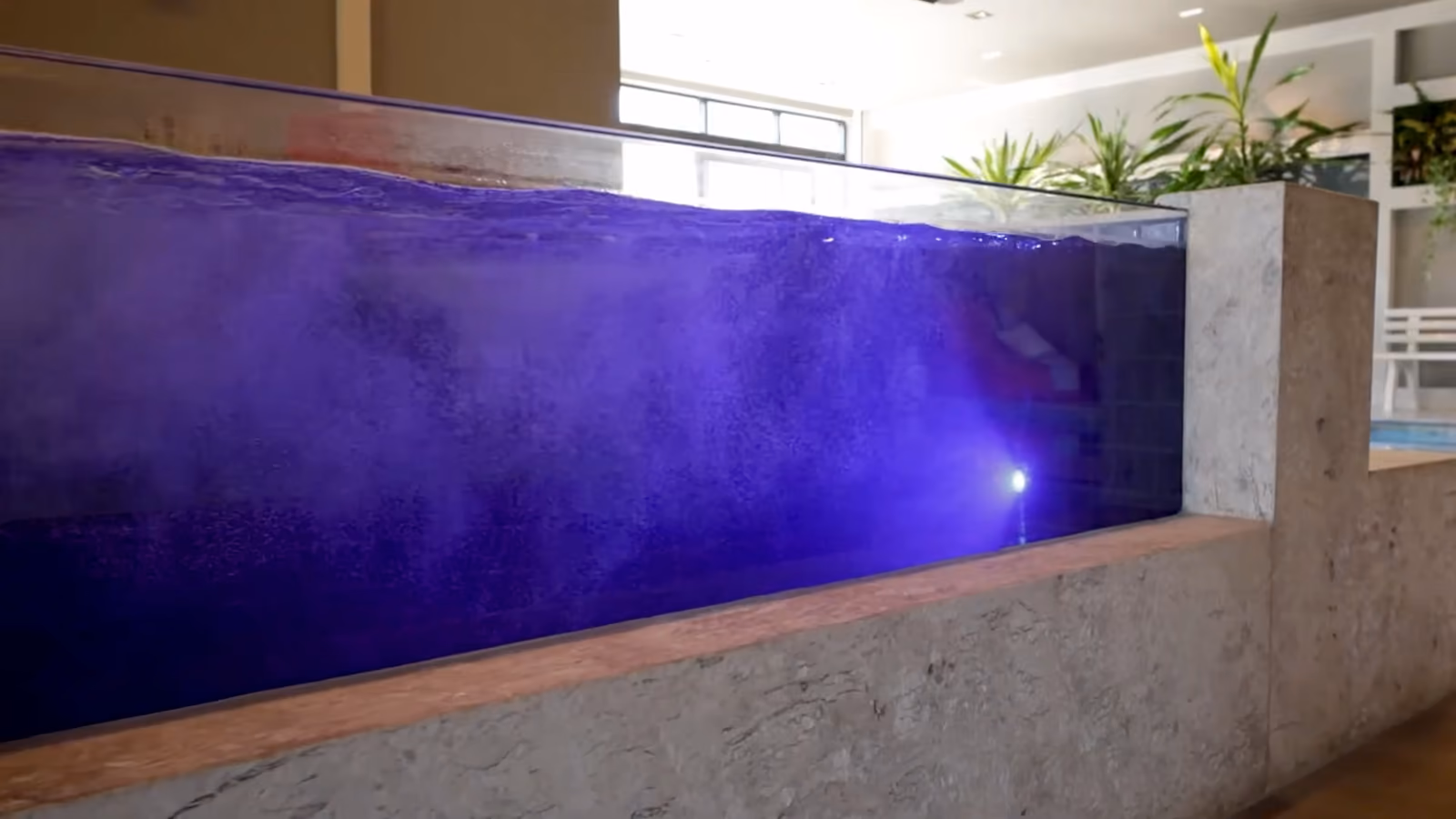 Gros plan sur une paroi transparente : l'eau éclairée se voit à travers.