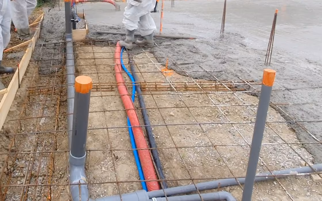 Ferraillage, tubes et gaines des réseaux en attente avant le coulage d'une plage de piscine, sur un chantier en France.