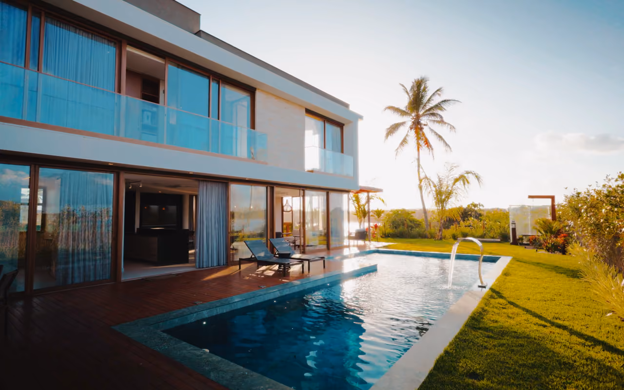 Villa contemporaine à étage, balcon vitré, piscine rectangulaire et jardin au soleil couchant.