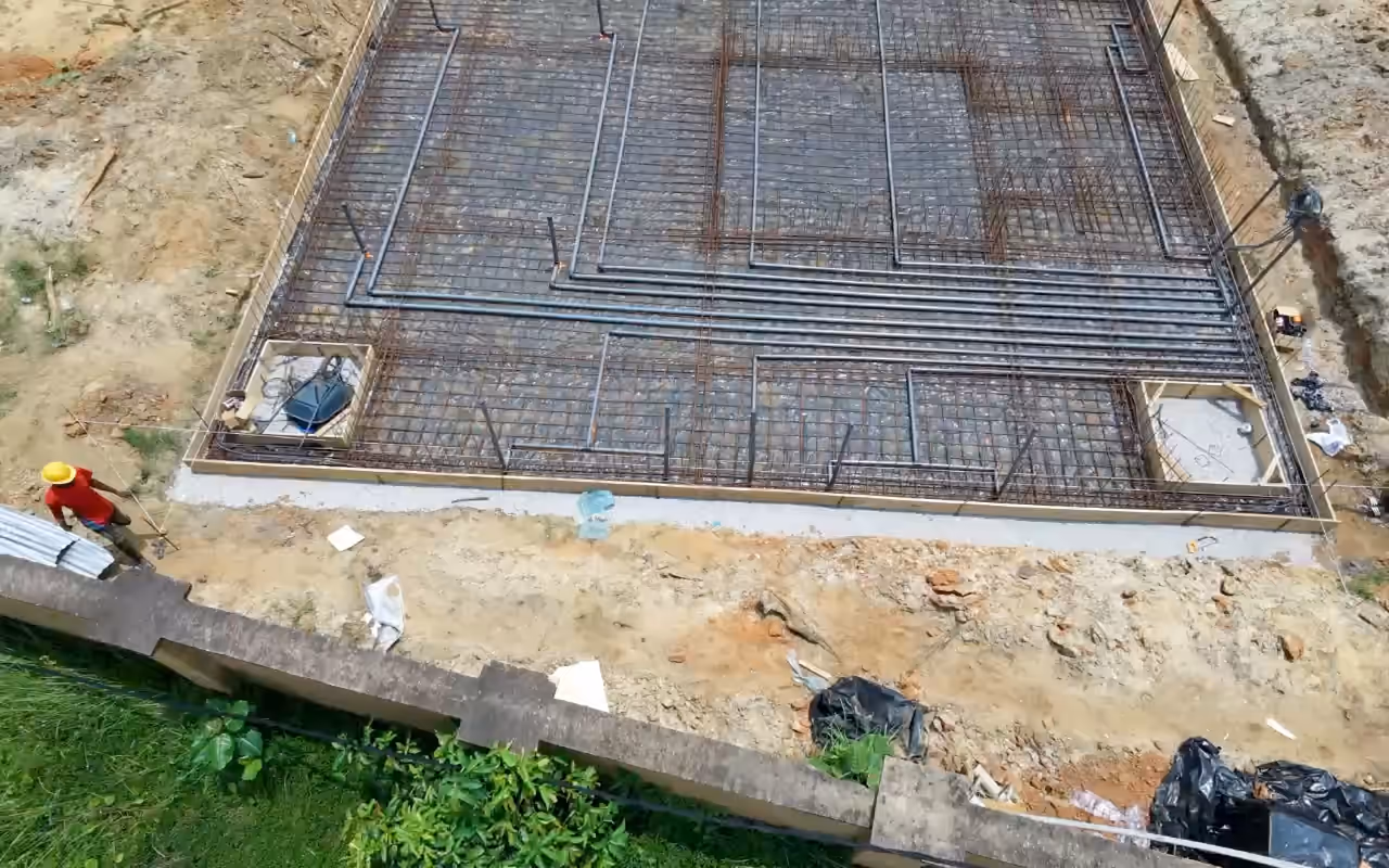 Vue de drone du radier ferraillé de Villa Park, vu de haut ; un ouvrier marche le long du coffrage.