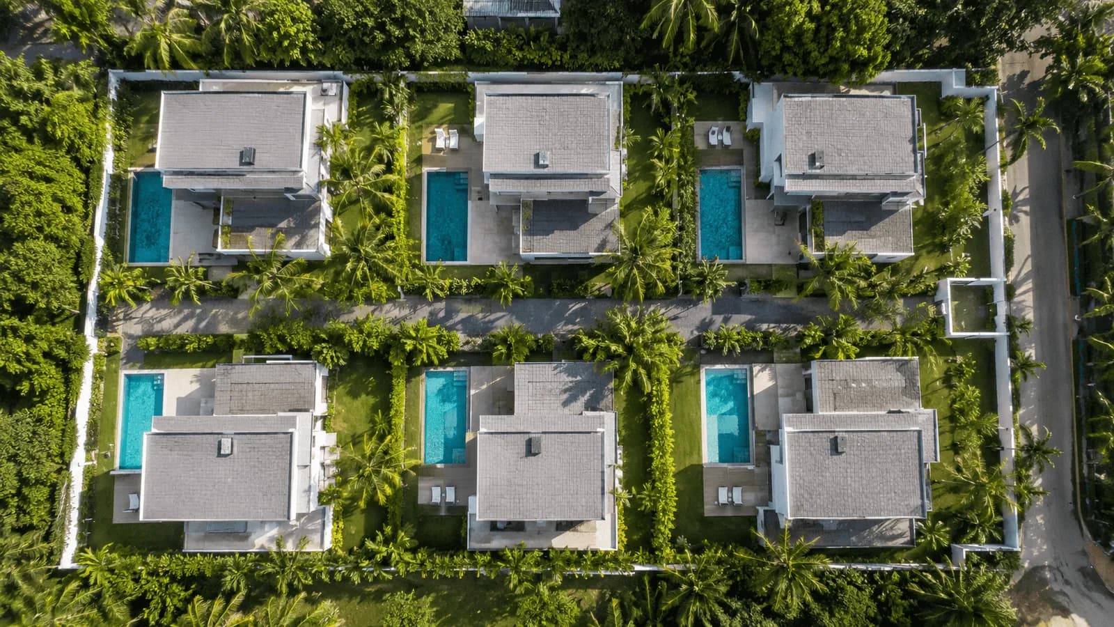 Six villas identiques avec piscine, vues du ciel, le long d'une voie interne.