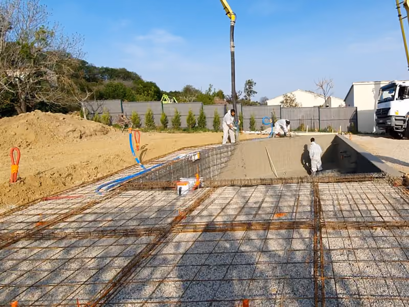 Le treillis de la future plage posé autour du bassin, la flèche de la pompe à béton au fond.