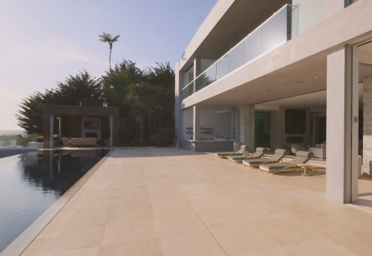 Villa contemporaine à étage, grande terrasse en pierre et piscine à débordement face à l'océan.