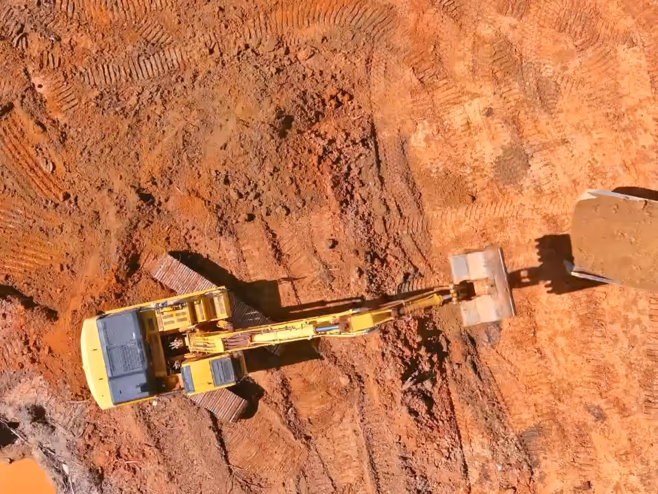 Terrassement vu du ciel : une pelle charge la latérite dans un camion.