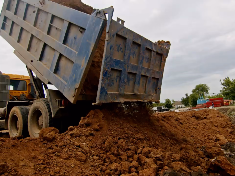 Un camion-benne déverse sa terre sur un chantier.