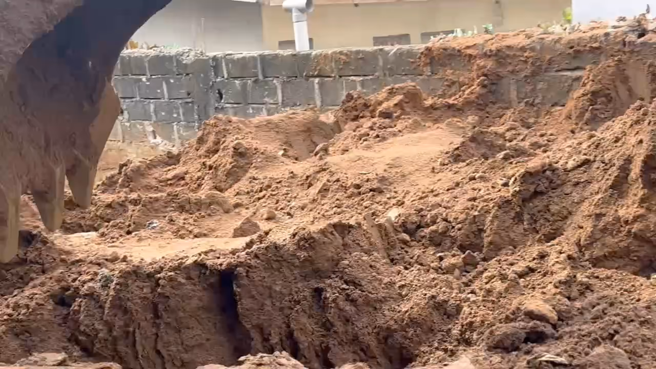 Gros plan : les dents du godet du tractopelle mordent la terre et poussent les mottes.