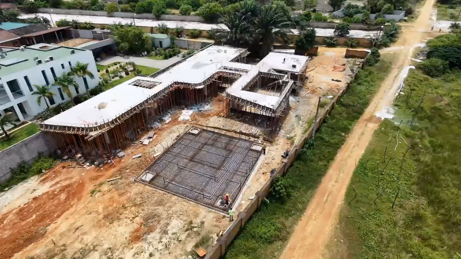 Villa Park vue du drone : avancée vers la villa en gros œuvre et son radier ferraillé, vue large du chantier, puis les équipes au travail le long du radier, vues du dessus.