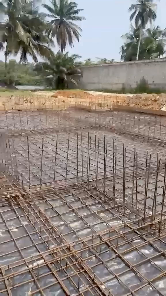 Le ferraillage du radier de Villa Park filmé au téléphone : nappe d'armatures au soleil devant les cocotiers, puis le bâtiment en coffrage étayé.
