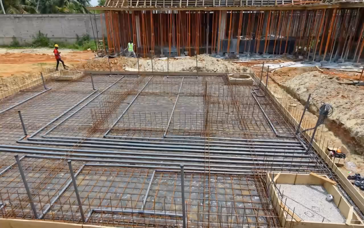 Chantier Villa Park : le radier ferraillé et ses réseaux en attente, vus de haut, ouvriers au fond près de la structure.