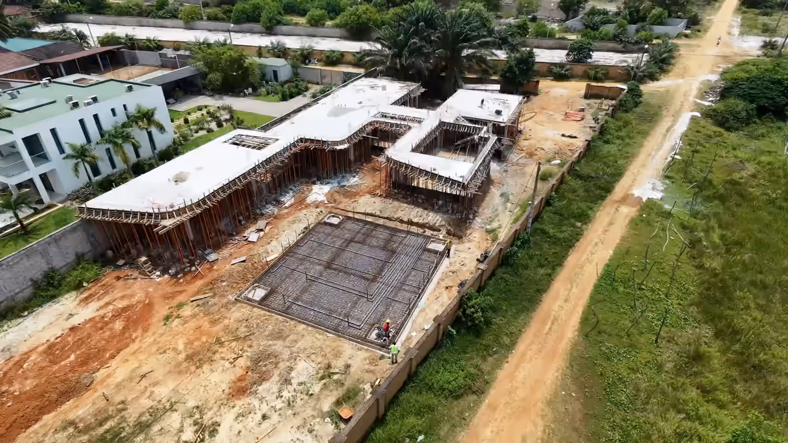 Le chantier Villa Park vu de haut : la structure en béton sous étais, le radier ferraillé, la piste et les terrains autour.