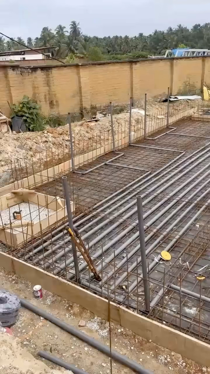 Vidéo filmée au téléphone sur le chantier Villa Park : le radier ferraillé et ses réseaux, deux ouvriers au fond.