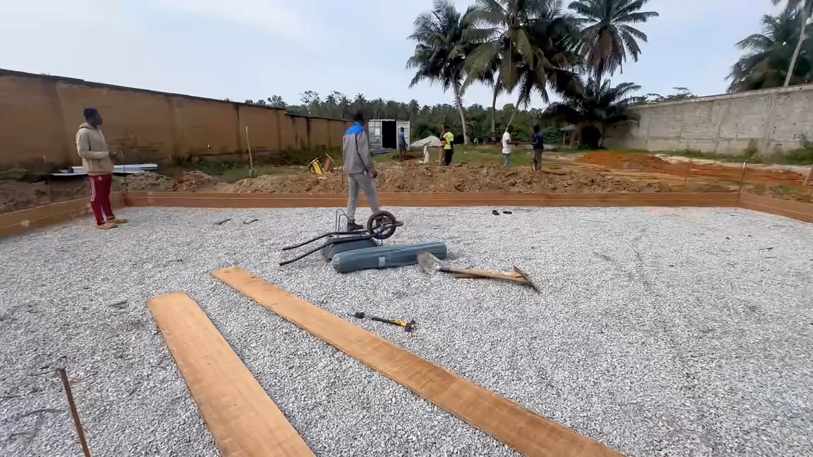 Chantier Villa Park au sol : le hérisson de gravier et ses planches de rive, puis deux ouvriers qui posent une planche.