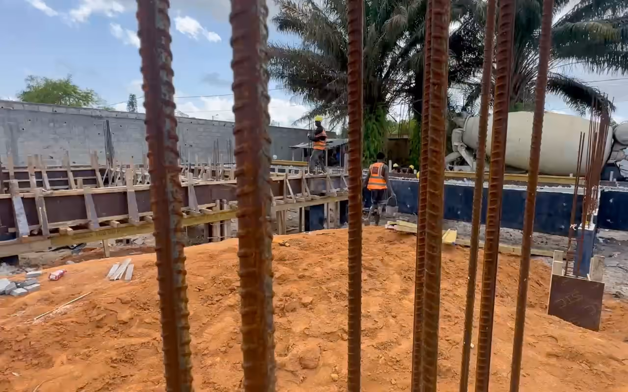 Chantier Villa Park : fers en attente au premier plan, longrines coffrées, toupie à béton au fond.