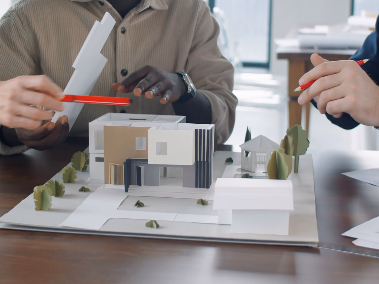 Pendant une réunion de conception, un crayon désigne la maquette d'une villa contemporaine.