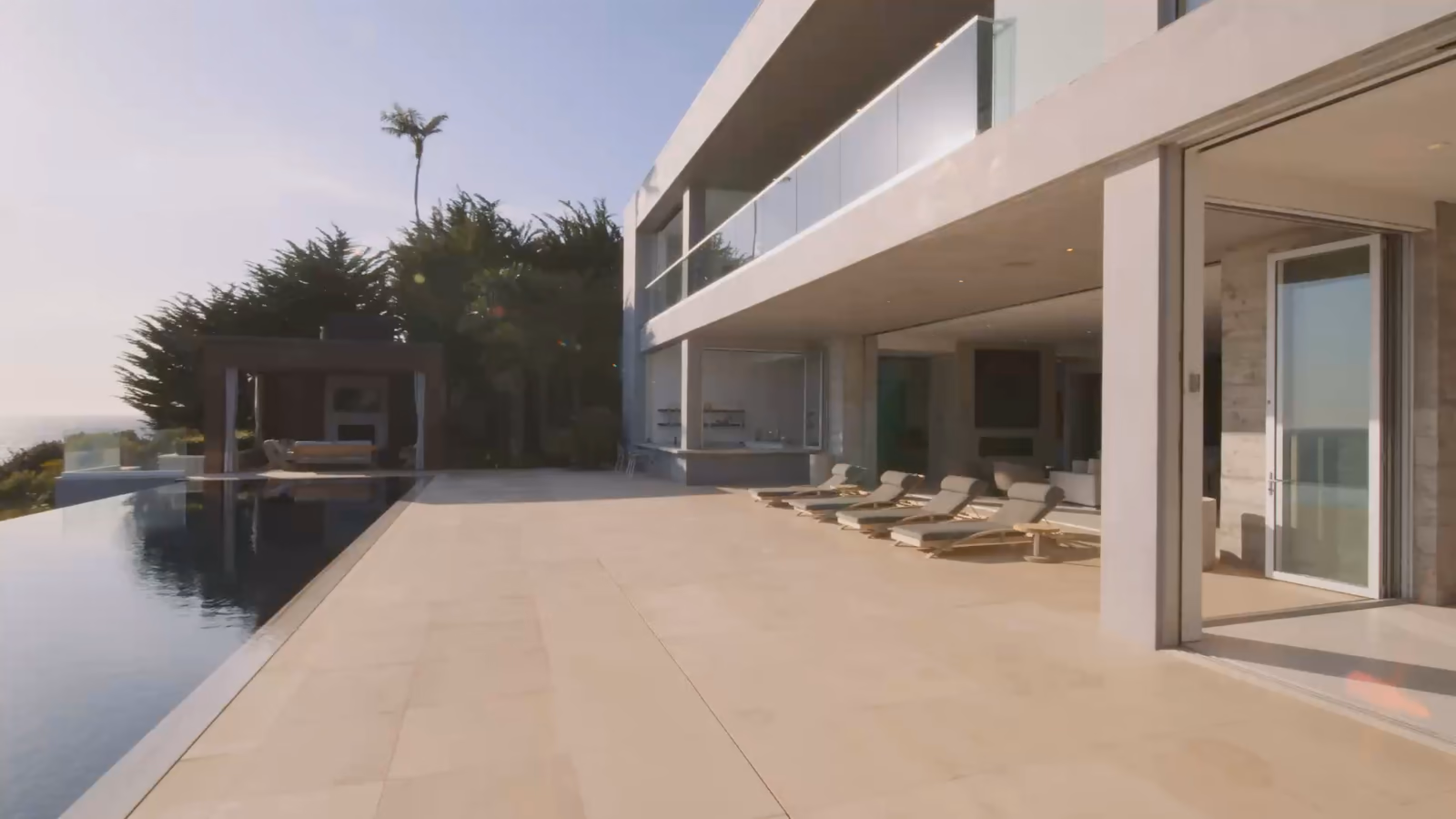 Villa à étage aux baies ouvertes sur une grande terrasse et une piscine à débordement, puis villa avec piscine dans son jardin clos, vue du ciel.