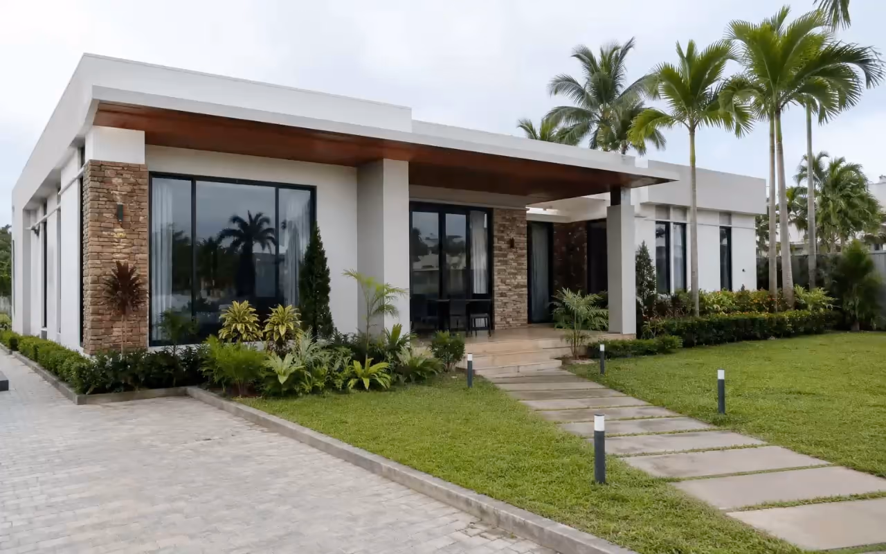 Villa contemporaine de plain-pied avec allée et pelouse ; villa de plain-pied au bord de l'eau au coucher du soleil.