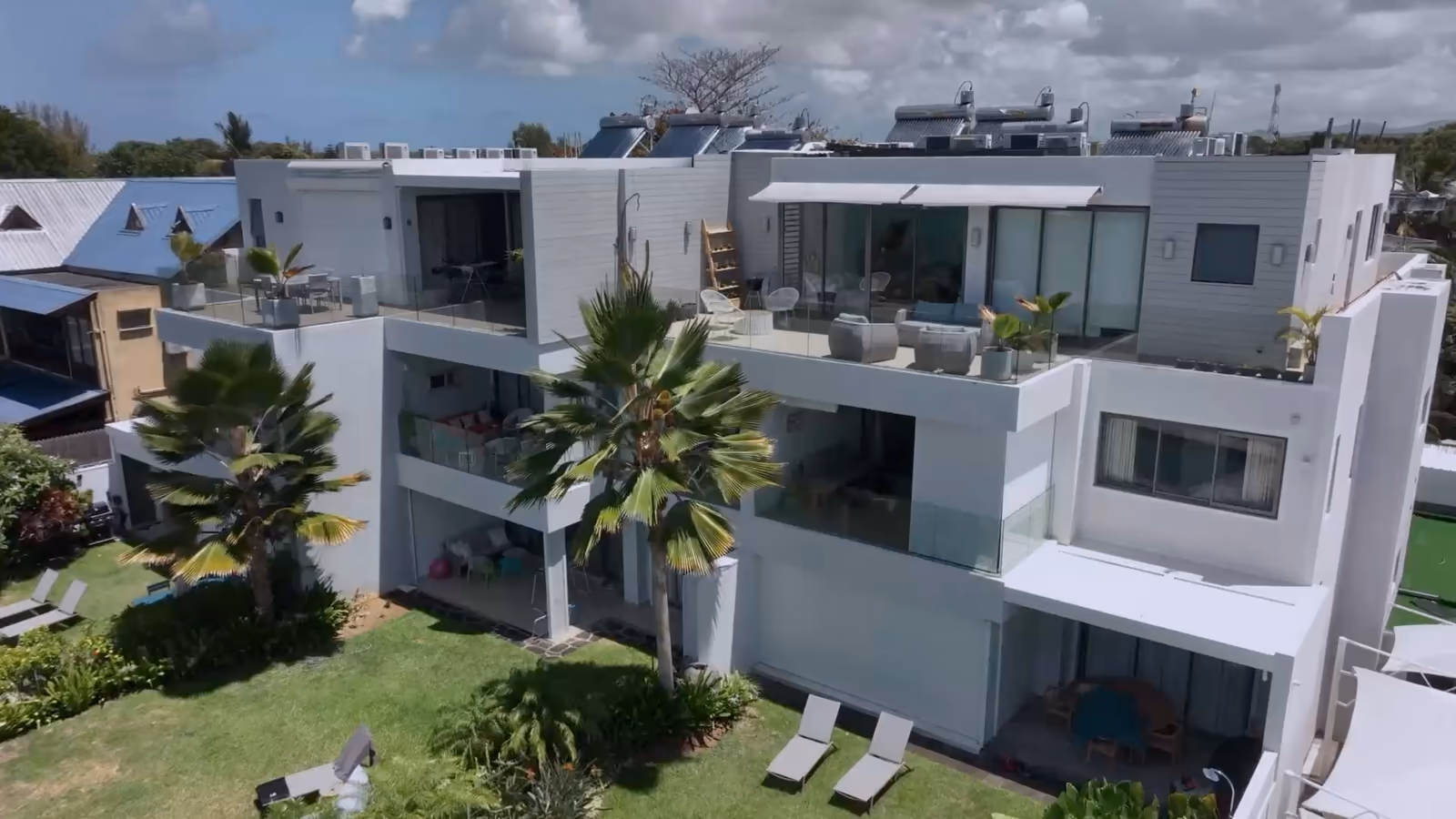 Résidence blanche à terrasses, jardin et piscine, vue du ciel.